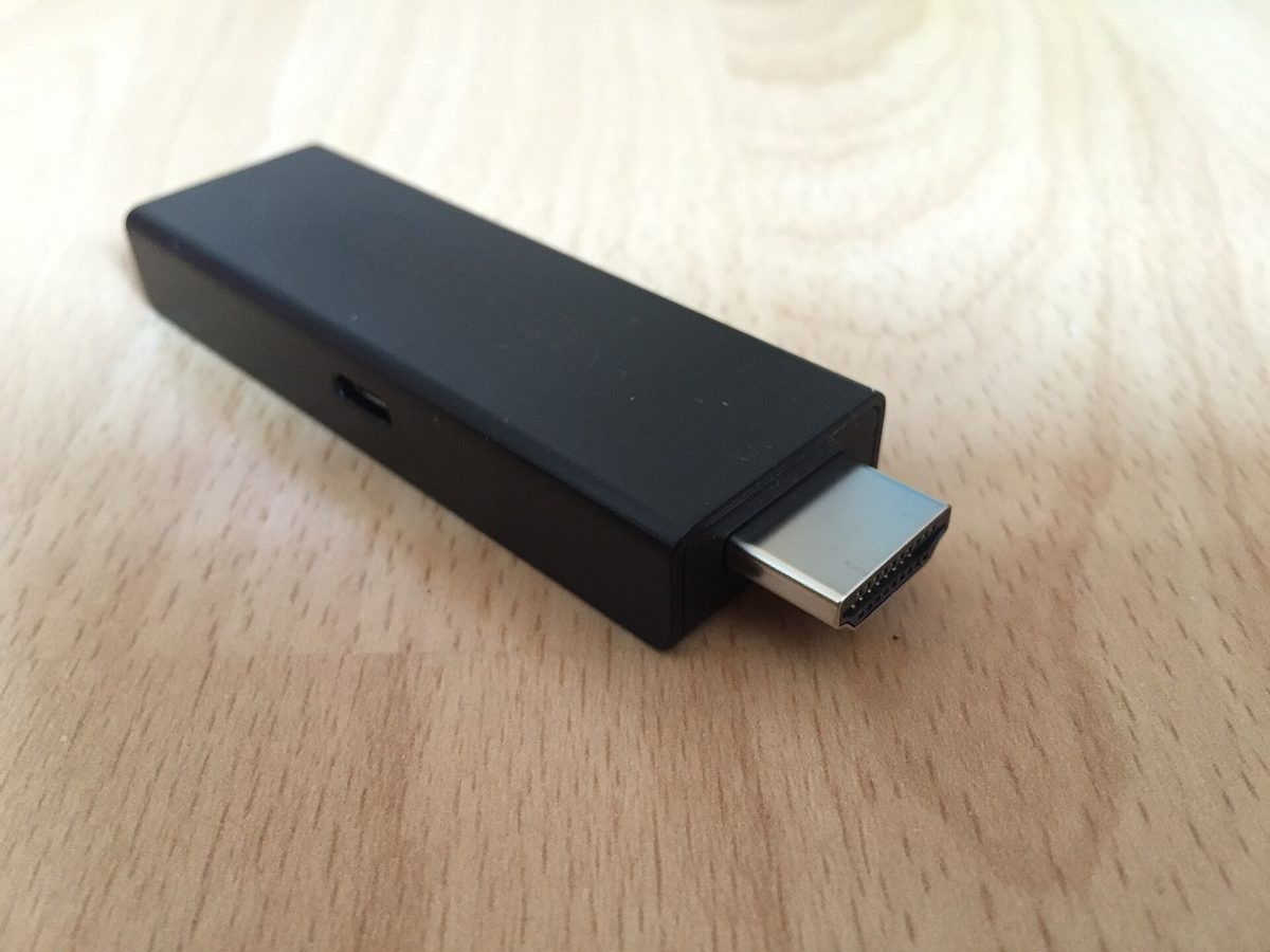 Amazon Fire TV Stick koblet til HDMI-porten på en TV, med IPTV-appens kanalmeny på skjermen